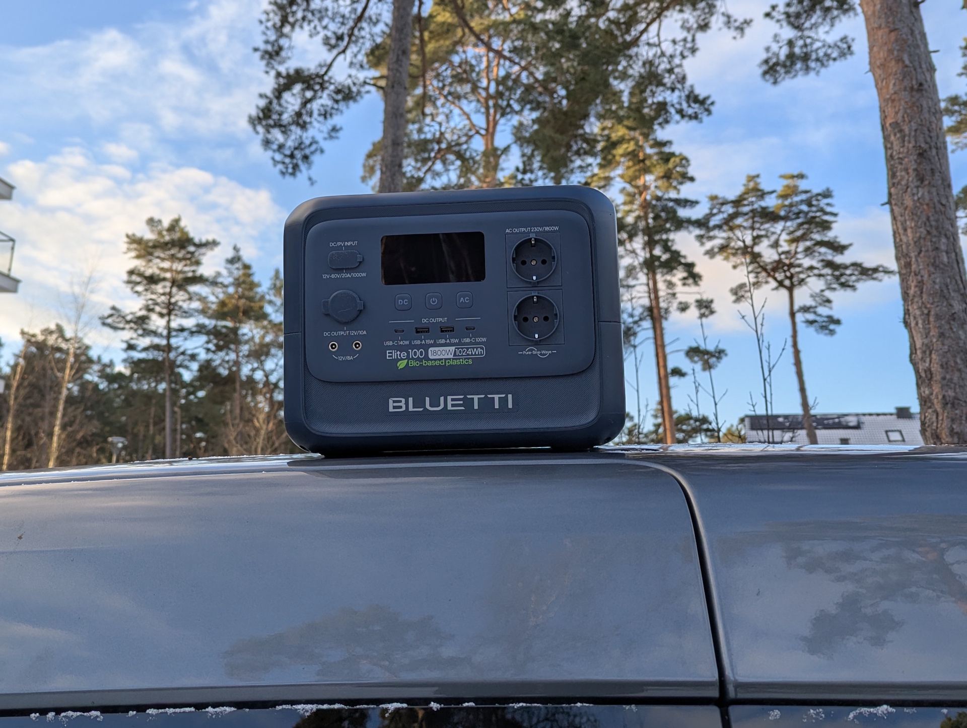 Bluetti Elite 100 V2 Bio-based på ett biltak med tallar i bakgrunden