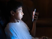 Tonåring i ett mörkt rum som tittar på en upplyst smartphone