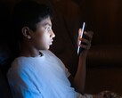 Tonåring i ett mörkt rum som tittar på en upplyst smartphone