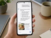 En hand som håller en smartphone som visar ett AI-svar med en sponsrad annons under