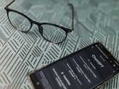 En smartphone med ChatGPT-appen öppen bredvid ett par glasögon på en mönstrad yta