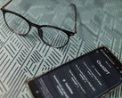 En smartphone med ChatGPT-appen öppen bredvid ett par glasögon på en mönstrad yta