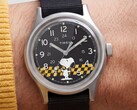 Närbild på Timex MK1:s svarta urtavla som visar Snoopy mot en gul- och svartrutig bakgrund med arabiska timmarkeringar och självlysande visare.