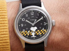Närbild på Timex MK1:s svarta urtavla som visar Snoopy mot en gul- och svartrutig bakgrund med arabiska timmarkeringar och självlysande visare.
