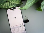 En smartphone med ChatGPT-appen öppen, vilande på en bärbar dator bredvid växtblad