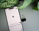 En smartphone med ChatGPT-appen öppen, vilande på en bärbar dator bredvid växtblad