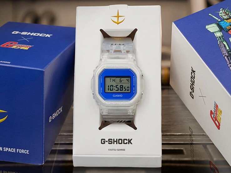 Casio G-Shock x Mobile Suit Gundam DW-5600 med transparent fodral och band, blå ram, E.F.S.F.-märke och samlarförpackning med Gundam-konstverk.