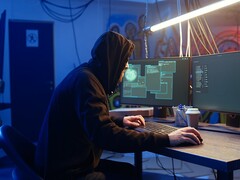 Generisk hackare vid en arbetsstation med dubbla skärmar som utför en attack mot en leverantörskedja.