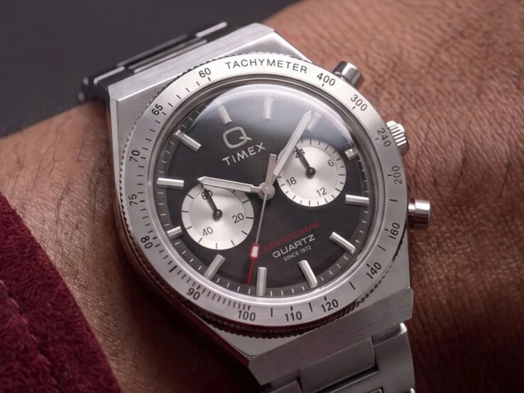 Timex Q Timex Continental Chronograph TW2Y93200 på en handled, med en svart radial urtavla i CD-stil, två silverfärgade hjälpurtavlor, takymeterring, självlysande markeringar och ett integrerat armband i rostfritt stål.