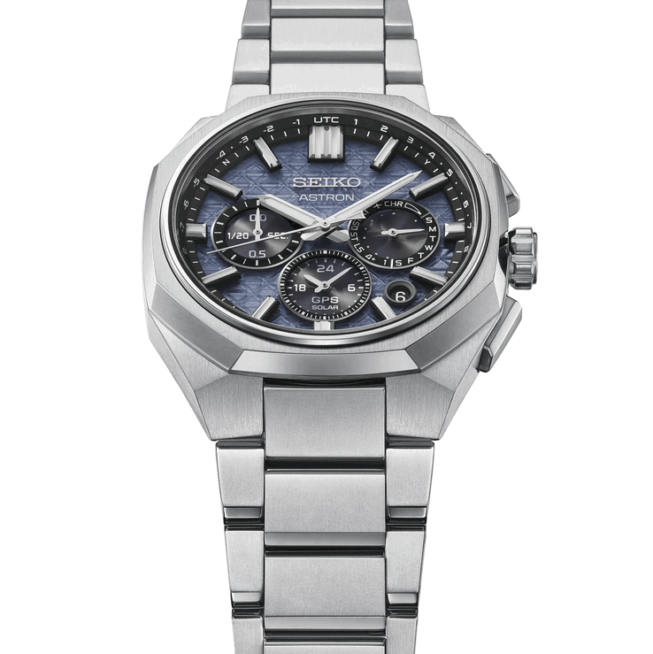 Vinklad frontvy av Seiko Astron HAB001 med fasetterad titanboett, integrerat armband och blå urtavla med textur.