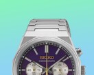 Närbild på den övre halvan av Seiko HGK003, med fokus på det kantiga boettet i rostfritt stål, de övre armbandslänkarna, de övre tryckknapparna och den övre delen av den lila urtavlan mot en livfull bakgrund med gröna och blåa färgövergångar.