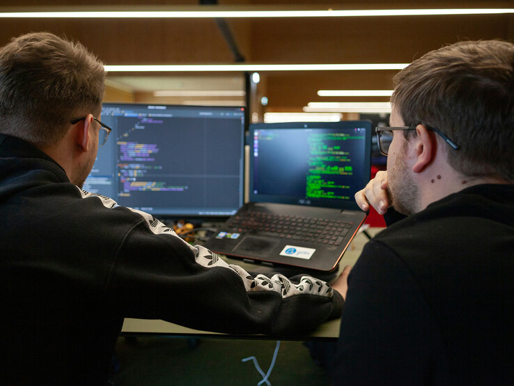 Forskare som analyserar kod på dubbla skärmar (Bildkälla: Flipsnack / Unsplash)
