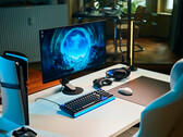 En stilren speluppställning i studion med en Sony Inzone M10S II-skärm på ett vitt skrivbord tillsammans med en vertikalt placerad PlayStation 5 Pro-konsol, ett mekaniskt tangentbord, en trådlös mus och ett headset med diskret blå belysning.