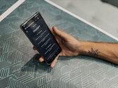 Hand som håller en smartphone med ChatGPT-appen öppen ovanför ett mönstrat bord
