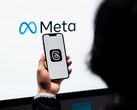 En hand håller en smartphone framför en stor Meta-logotyp