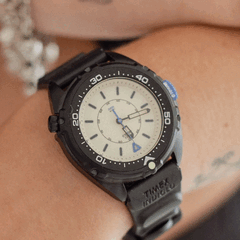 Timex Intrepid x Dimepiece Blackout Edition har en svart boett i rostfritt stål, en krämfärgad urtavla och lila detaljer