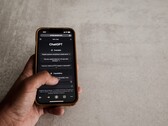 Hand som håller en smartphone som visar ChatGPT-gränssnittet ovanför en grå stenyta