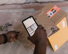 En hand håller en smartphone ovanför ett paket och skannar dess streckkod