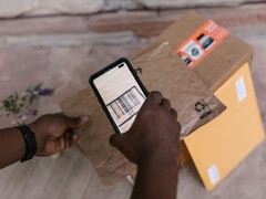 En hand håller en smartphone ovanför ett paket och skannar dess streckkod