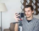 En ung man filmar sig själv hemma med en smartphone monterad på ett stativ