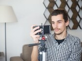 En ung man filmar sig själv hemma med en smartphone monterad på ett stativ