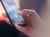 En hand håller i en smartphone och låser upp den med hjälp av fingeravtryckssensorn på låsskärmen.