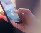 En hand håller i en smartphone och låser upp den med hjälp av fingeravtryckssensorn på låsskärmen.