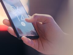 En hand håller i en smartphone och låser upp den med hjälp av fingeravtryckssensorn på låsskärmen.