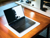 En öppen, matt svart Razer Blade 16-speldator som står på en vit skrivbordsmatta ovanpå ett varmt träbord, med en livfull svartvit bakgrundsbild.