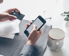 Person som trycker på en smartphone medan hen håller ett bankkort i den andra handen