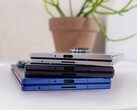 Stapel av hopfällbara smartphones som representerar konceptet för den kommande Apple iPhone Fold, placerad på ett vitt bord med en krukväxt i bakgrunden (Bildkälla: Notebookcheck)