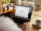 Person vid en bärbar dator med Googles startsida öppen, bredvid en kopp kaffe