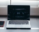 Öppna en bärbar dator och en smartphone bredvid varandra på ett skrivbord i dagsljus