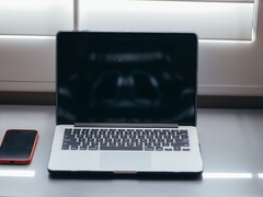 Öppna en bärbar dator och en smartphone bredvid varandra på ett skrivbord i dagsljus