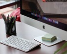 En iMac på ett skrivbord med macOS-docken synlig på skärmen och ett Apple-tangentbord framför
