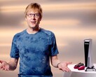  Mark Cerny under ett PlayStation-event, sittande bredvid en PS5-konsol och DualSense-kontroller. (Bildkälla: Sony Interactive Entertainment)