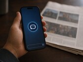 En hand håller en smartphone med en chatbot-ikon, och bredvid den ligger en tryckt tidning.