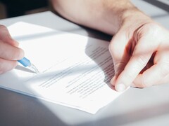 En hand undertecknar ett dokument med en blå kulspetspenna