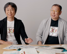 En skärmdump av Shigru Miyamoto och Tezuka Takashi med t-shirts från 30-årsjubileet av Super Mario Bros