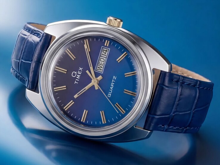 Produktbild av Timex Q 1976 Day and Date tagen i vinkel, som framhäver urtavlan med blå färggradient, den polerade boetten i rostfritt stål och den guldfärgade kronan.