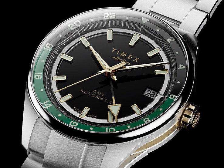 Sned vy av Timex Atelier GMT Première M1a som visar dess svarta urtavla, gröna GMT-ring, guldfärgade krona och armband i rostfritt stål.