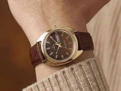 Timex Q 1978 Day and Date med en brun fuméurtavla och guldfärgad boett, visad på en handled med ett brunt läderarmband.