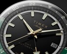 Närbild av Timex Atelier GMT Première M1a:s svarta urtavla med guldfärgade visare, självlysande timmarkörer, datumfönster och en svart och grön 24-timmars GMT-ring.