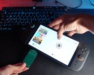 Yu från YouTube-kanalen Better Gaming håller en Nintendo Switch 2 i ena handen och en grön PCB-adapter med öppen källkod i den andra, och försöker sätta in den i enhetens microSD Express-kortplats (Bildkälla: Better Gaming via YouTube)