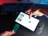 Yu från YouTube-kanalen Better Gaming håller en Nintendo Switch 2 i ena handen och en grön PCB-adapter med öppen källkod i den andra, och försöker sätta in den i enhetens microSD Express-kortplats (Bildkälla: Better Gaming via YouTube)