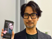 Hideo Kojima visar en affisch för Physint på sin telefon