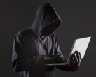 En hacker med huva som använder en bärbar dator mot en mörk bakgrund.