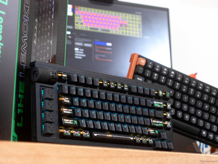 Genomskinliga tangentbordskåpor på Lemokey L1 HE-tangentbord på ett skrivbord framför en bärbar dator och K4 HE-tangentbord