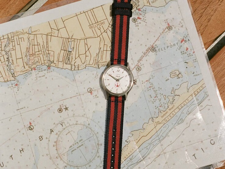 Noah x Timex MK1 Anchor-klocka med ett marinblått och rött randigt tygarmband som vilar på en sjökort.