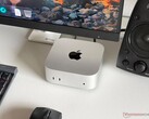 En Apple M6 Mac mini på ett skrivbord i en speluppsättning med skärm, tangentbord, mus och högtalare.